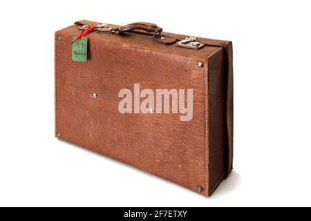 Old retro or vintage suitcase made of brown leather isolated on white background. Happy holidays tag is visible on the suitcase. Stock Photo