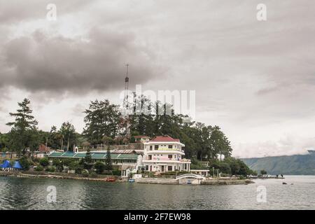 Volcanic Island of Samosir on the lake of Toba, on northern Sumatra, Visible typical houses and christian church on the island on a cloudy day. Stock Photo