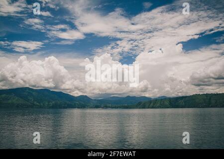Overview of the lake Toba in the northern Sumatra, on a cloudy day with big white puffy clouds. Stock Photo