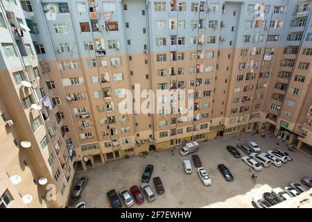 Old panel house. A view of the serial high-rise apartment buildings in Baku suburbs with the view of the parking lot underneath it. Stock Photo