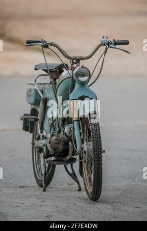 Frontal view of an old blue moped or scooter from the 1950 or fifties. Retro vintage moped parked on asphalt parking lot. Stock Photo