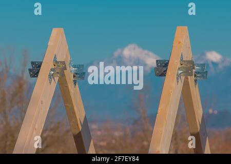 Modern wooden roof frame or frames, framework with trusses on a renovated house. Mountains in the background Stock Photo
