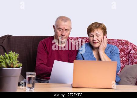 Couple senior using computer laptop on sofa at home for online shopping, surfing internet, e commerce, living room, indoor office Stock Photo