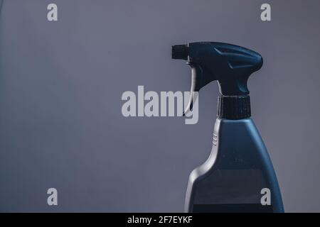 Side view of a plastic spray bottle for cleaning and operating it. Drops from bottle are being sprayed all over the place. Side view of an operational Stock Photo