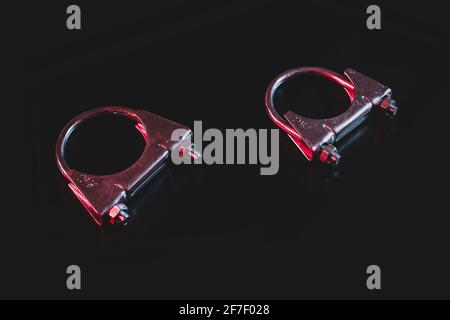 Two exhaust hose clamps isolated on black in modern red and blue dramatical lighting. Stock Photo