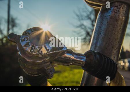 Detail of cheap worn number combination lock on an old bicycle, with sun streak or flare just behind the lock. Park setting or outside in suburb of a Stock Photo