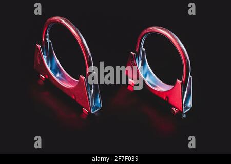Two exhaust hose clamps isolated on black in modern red and blue dramatical lighting. Stock Photo
