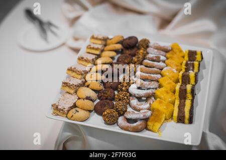 An assortiment of sweets on a white plate at a banquet or a party. Catering with cookies and cakes. Stock Photo