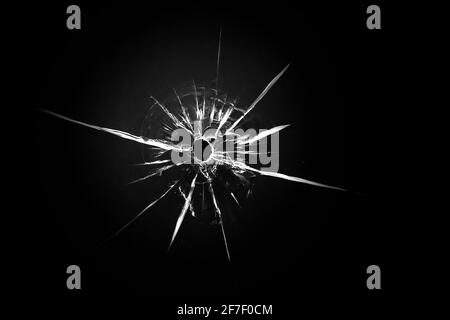 Cracked texture on a black background. Broken glass bullet from a shot. Stock Photo