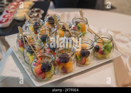 An assortiment of dessert fruit on a white plate at a banquet or a party. Catering with fruit in glass jars. Stock Photo