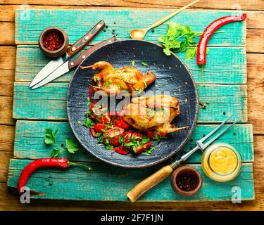 Roasted whole quails and spring vegetable salad on rustic wooden table Stock Photo