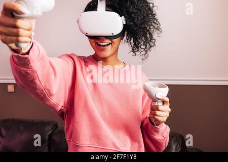 Young African American female in VR goggles and with joysticks experiencing augmented reality Stock Photo