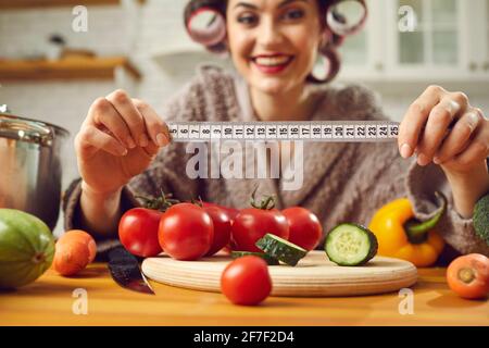 Measure tape in young woman housewife hand over fresh organic vegetables Stock Photo