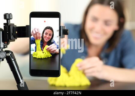 Happy influencer recording video with smaprt phone playing with cinetic sand at home Stock Photo