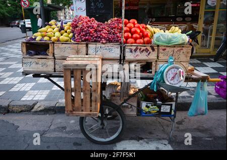 Cordoba, Argentina - January, 2020: Street counter on wheels with with old scales and wooden boxes full of fruits and vegetables such as pears, grapes Stock Photo