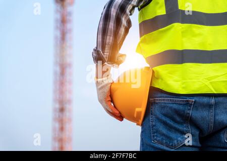 Engineer technician holding helmet in construction site and construction site worker background safety first concept. Stock Photo