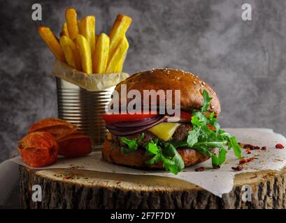 Craft beef burger and fries on a wooden table on a dark background. Stock Photo