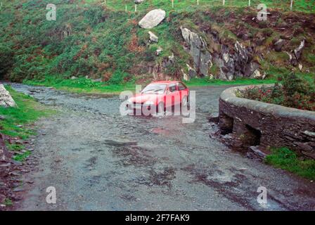 a car going through a stram that is flowing across a road, September 1990, Dingle Peninsula, Co. Kerry, Ireland Stock Photo