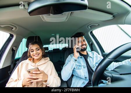 Young couple on the red car, man using moblie phone in a car. Stock Photo