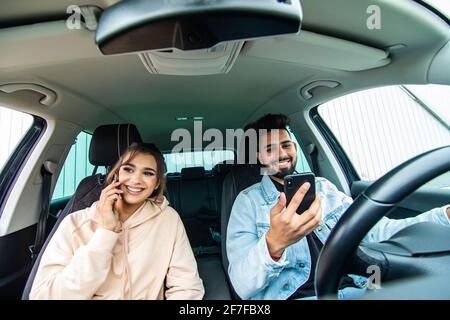 Young couple on the red car, man using moblie phone in a car. Stock Photo