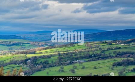 Scenic Wharfedale countryside (green valley, undulating hills, upland fells, sunlight on farmland fields, dramatic sky) - West Yorkshire, England, UK.