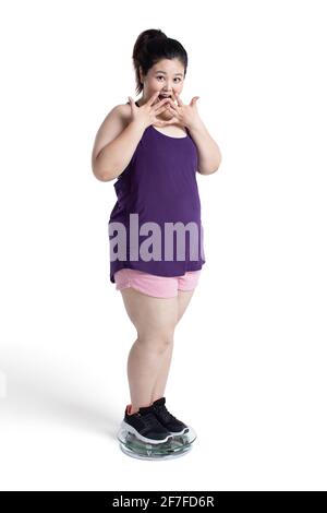 Overweight young woman weighing herself on a scale Stock Photo