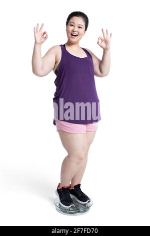 Overweight young woman weighing herself on a scale Stock Photo