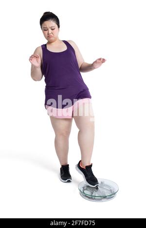Overweight young woman weighing herself on a scale Stock Photo