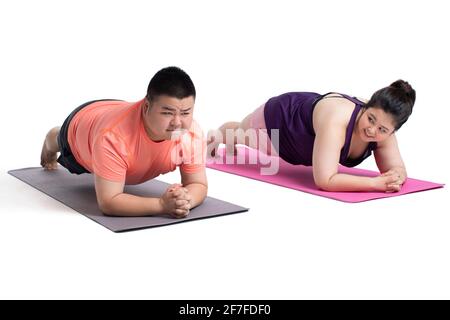 Overweight young couple doing plank position Stock Photo