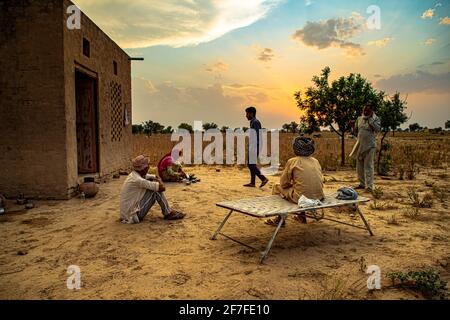 indian farmers family sit in the middle,taking a break in the field during harvesting crops.beautiful clouds in background. Stock Photo