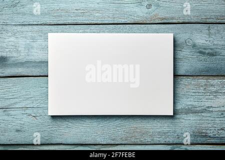 White canvas hanging on light blue wooden wall. Mockup wall decor