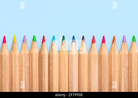 Row of colorful wooden pencils on a blue background Stock Photo