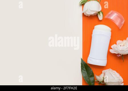 white Deodorant or antiperspirant with white flowers roses on orange background with copy space, template Stock Photo