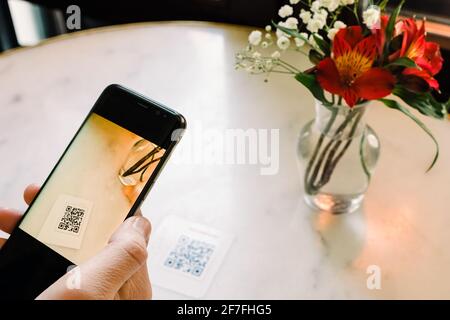 Man scanning the QR code with mobile phone at the restaurant. Stock Photo