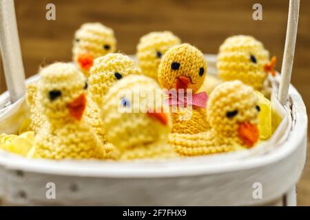 Cute knitted chicks containing chocolate eggs in an Easter basket Stock Photo