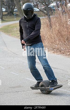 A  man riding a ONEWHEEL, a self-balancing single wheel electric board-sport, recreational personal transporter, described as an electric skateboard. Stock Photo