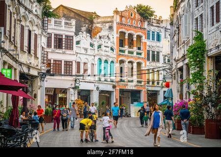 Haikou China , 21 March 2021 : Qilou old street view a pedestrian road with colorful arcade buildings with people and dramatic sunset light in Haikou Stock Photo