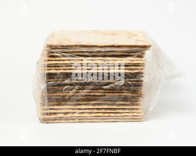 baked square matzo in a transparent bag on a white background, close up Stock Photo