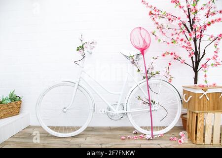 Retro Bicycle with flowers on background of white house shot from front to back yard. Garden decor in Provence style Stock Photo
