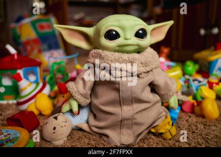 April, 2021: Baby Grogu, baby Yoda stands among the colorful toys. Realistic toy. Blurred background Stock Photo