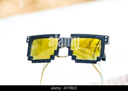 Yellow lenses pixel 8bit sunglasses design shoot in a summer day closeup.Thug life model. Selective focus Stock Photo