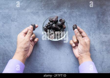 man hand eating fresh date fruit in a bowl on table  Stock Photo
