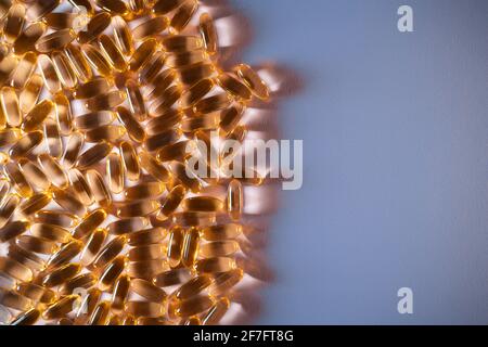 handful of golden fish oil capsules omega 3 vitamins on purple background Stock Photo