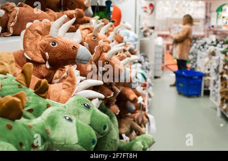 Close-up of toy dinosaurs on store shelves. Blurry shoppers in the background. Stock Photo