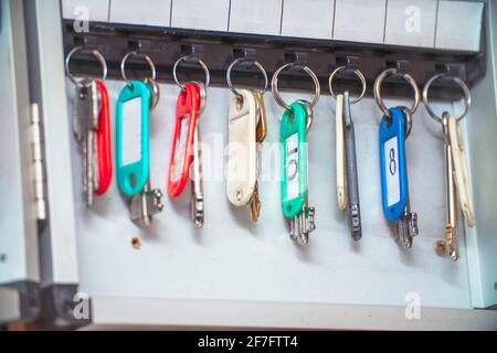 The keys to the doors with tags hang on hooks in a special drawer. Selective focus Stock Photo