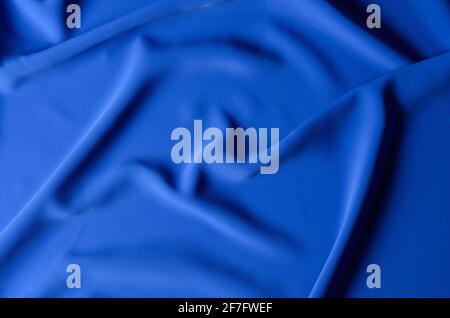 The background is made of a delicate blue chiffon fabric with folds in the form of waves. Top view. Selective focus. Stock Photo