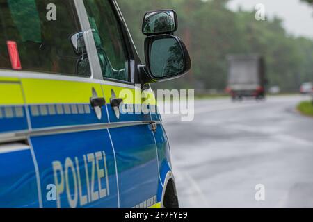 Side view of German police car with motorway in the background. Mirror window body from the passenger side with yellow and blue paintwork. Emergency b Stock Photo