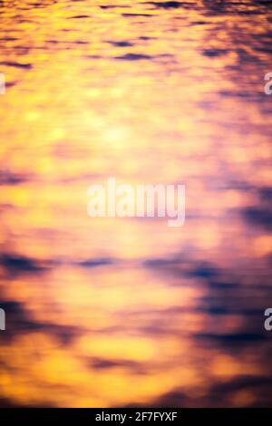Defocused texture of sea and ocean waves with the warm ananrjand colors of sunrise or sunset. Nature background. Stock Photo