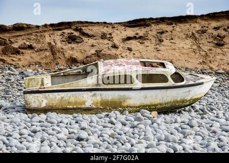Ship wreck of an old boat washed up on a rocky beach Stock Photo