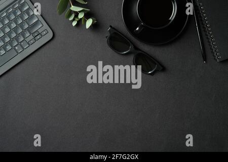 Top view creative workspace with laptop computer, cop of coffee, glasses and supplies on black leather background. Flat lay, view from above. Stock Photo
